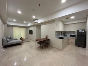 eine Küche und ein Wohnzimmer mit einem Tisch und einer Couch in der Unterkunft Podomoro Delipark Apartemen Cozystay Empire Tower 3BR Medan in Medan