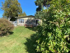 a stone house behind a bush in front of a yard at Évasion sur l'Isle - spa in L'Isle-aux-Coudres