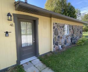 a front door of a house with a stone wall at La petite maison sur l'Isle in L'Isle-aux-Coudres