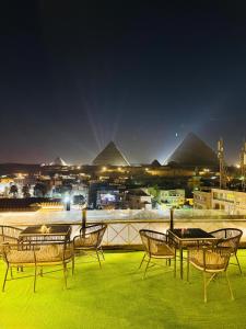 a group of chairs and tables on a roof with pyramids at Kayan Pyramids View in Cairo