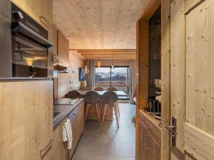 a kitchen with wooden cabinets and a table and chairs at Duplex confortable au cœur de Val Thorens, balcon, proche des pistes, accepte les animaux - FR-1-640-79 in Val Thorens