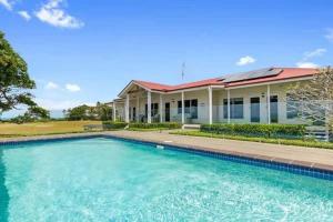 a large swimming pool in front of a house at Beachfront Hervey Bay Homestead in River Heads