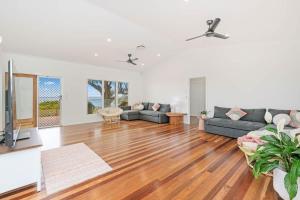 a living room with a couch and a television at Beachfront Hervey Bay Homestead in River Heads +61 photos