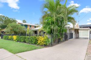 a palm tree in front of a house with a fence at Kiesha House Beachfront Serenity in Point Vernon