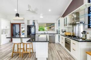 a large kitchen with white cabinets and black counter tops at Sunset Shores Escape in Point Vernon +47 photos
