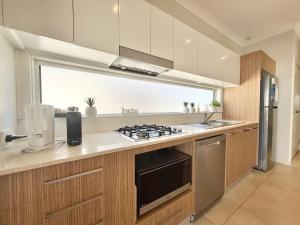 a kitchen with a stove top oven next to a window at Villa Oceania at Caves Beach Villas in Caves Beach