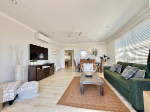 a living room with a green couch and a table at Villa Oceania at Caves Beach Villas in Caves Beach