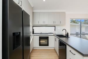 een keuken met witte kasten en een zwarte koelkast bij Bay Breeze Beachhouse in Scarness