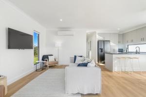 a white living room with a white couch and a kitchen at Bay Breeze Beachhouse in Scarness