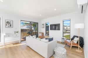 een witte woonkamer met een witte bank en stoelen bij Bay Breeze Beachhouse in Scarness +48 foto's