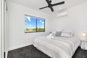 a white bedroom with a large bed and a window at Bay Breeze Beachhouse in Scarness