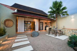 a patio of a house with a table and a palm tree at Ubu Villa Lemme with Rustic Mediterranean Style in Adi Sutjipto