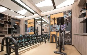 重慶市にあるThe Mustel Hotel Chongqing Hongyadongのトレッドマシンと壁にポスターが貼られたジム
