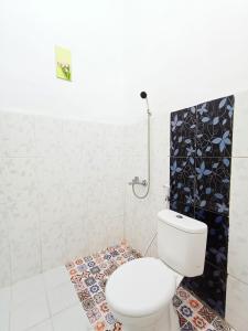 ein weißes Badezimmer mit Toilette und Dusche in der Unterkunft RedDoorz Syariah near Universitas 17 Agustus Banyuwangi in Banyuwangi