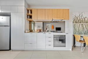 a kitchen with white cabinets and a refrigerator at Vine Apartments South Brisbane in Brisbane +9 photos