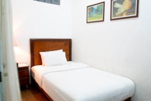 a small bedroom with a bed and a night stand at Omah Kebon Guest House in Temanggung