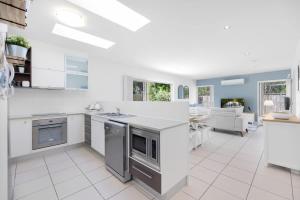 a kitchen with white appliances and a living room at Private Poolside Villa in Urangan
