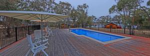 eine Terrasse mit Stühlen, einem Sonnenschirm und einem Pool in der Unterkunft Sommerville Valley Tourist Park & Resort in Stanthorpe