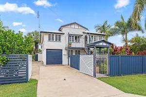 una casa blanca con una puerta y una valla en The Tropics Resort Style Pool, en Urangan