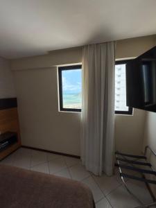 - une chambre dotée d'une fenêtre offrant une vue sur l'océan dans l'établissement Quality suites natal apto 1009, à Natal