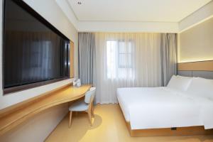 上海市にあるJI Hotel Shanghai Zhongxing Roadのベッドと机、テレビが備わったホテルの部屋