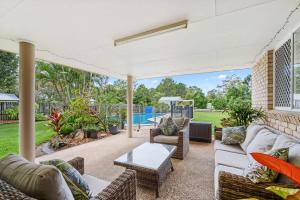 an outdoor patio with couches and a table at Private Family Retreat - Pool Spa Tennis firepit in Hervey Bay