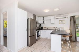 a kitchen with white cabinets and a stainless steel refrigerator at Sea King - Duplex Walk to Beach in Urangan