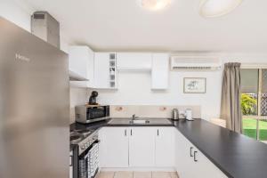 a white kitchen with a sink and a microwave at Sea King - Duplex Walk to Beach in Urangan