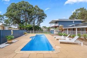 a swimming pool with lounge chairs and a house at Whitesands Family Beachhouse in Urangan