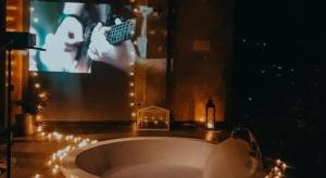 a bathroom with a tub with a tv and a person holding a remote at Baan Hom Muen Li in Mae Salong +242 photos