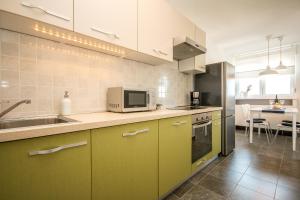 a kitchen with green cabinets and a sink and a microwave at Hendrix Bridge Apartment in Zagreb