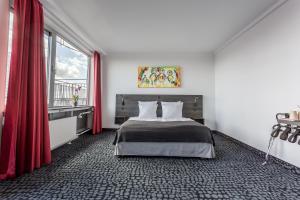 a bedroom with a bed with red curtains and a window at ProfilHotels Mercur in Copenhagen