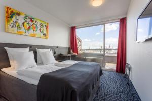 a hotel room with a bed and a large window at ProfilHotels Mercur in Copenhagen