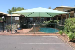a fence with a green umbrella in front of a house at Lake Forbes Motel in Forbes