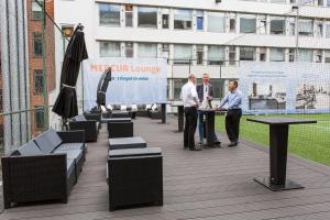 three men are standing at a table on a balcony at ProfilHotels Mercur in Copenhagen