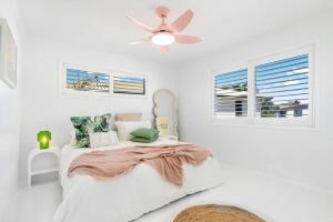 a white bedroom with a bed with a ceiling fan at The Springs Villa 1 in Urangan