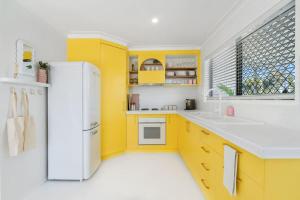a kitchen with yellow cabinets and a white refrigerator at The Springs Villa 1 in Urangan