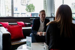 a man sitting at a table talking to a woman at ProfilHotels Mercur in Copenhagen