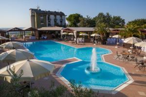 una piscina con una fuente, mesas y sombrillas en La Cantinella, en Ostra