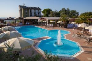 a pool with a fountain and tables and umbrellas at La Cantinella in Ostra