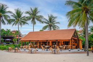 a restaurant on the beach with palm trees at Furama Resort Danang in Danang