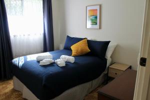 a bedroom with a blue bed with towels on it at Smugglers Cove in Esperance