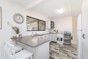 a kitchen with white appliances and a clock on the wall at Coastal Cottage in Urangan