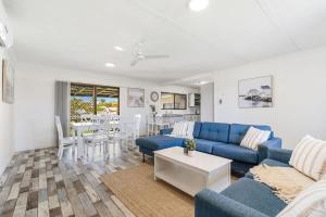 a living room with a blue couch and a table at Coastal Cottage in Urangan