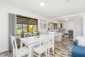 a kitchen and dining room with a white table and chairs at Coastal Cottage in Urangan