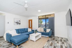 a living room with blue couches and a tv at Coastal Cottage in Urangan