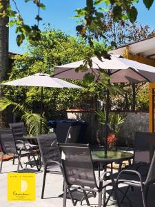 an outdoor patio with tables and chairs and umbrellas at Mini Suite - Pousada Lemon com Cozinha - Sesc Bertioga - Ar Condicionado e Frigobar in Bertioga