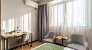 a hotel room with a bed and a desk and chairs at Green Tree Inn Hefei Railway Station International Auto Market Zhusitan Metro Station in Hefei