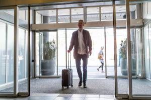 un uomo che cammina in un aeroporto con una valigia di ProfilHotels Mercur a Copenaghen