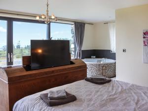 a bedroom with a bed with a television and a tub at Snowdon Summit View in Llanllyfni